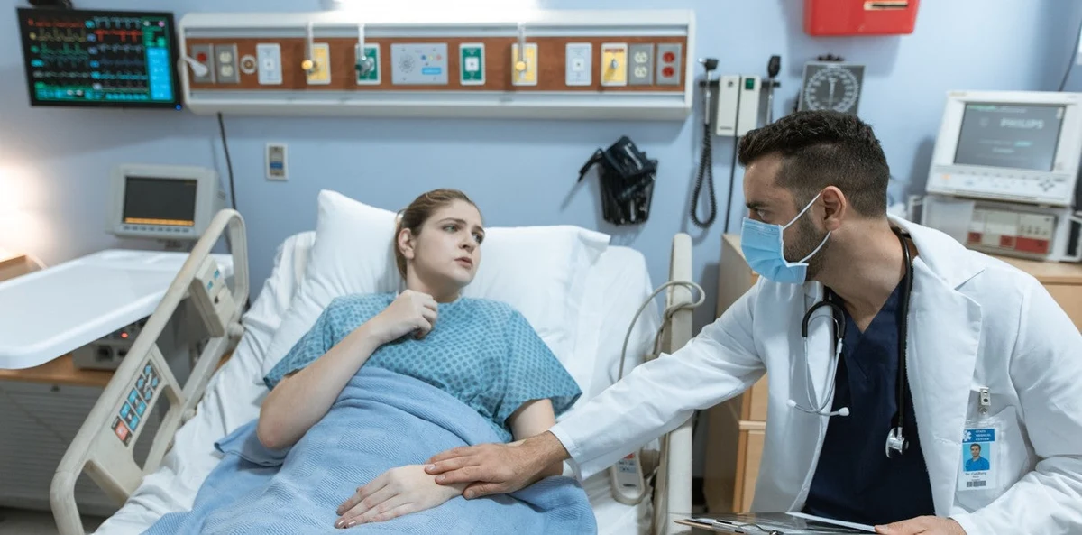 Doctor consulting a female patient on a hospital bed about sexual health and wellness